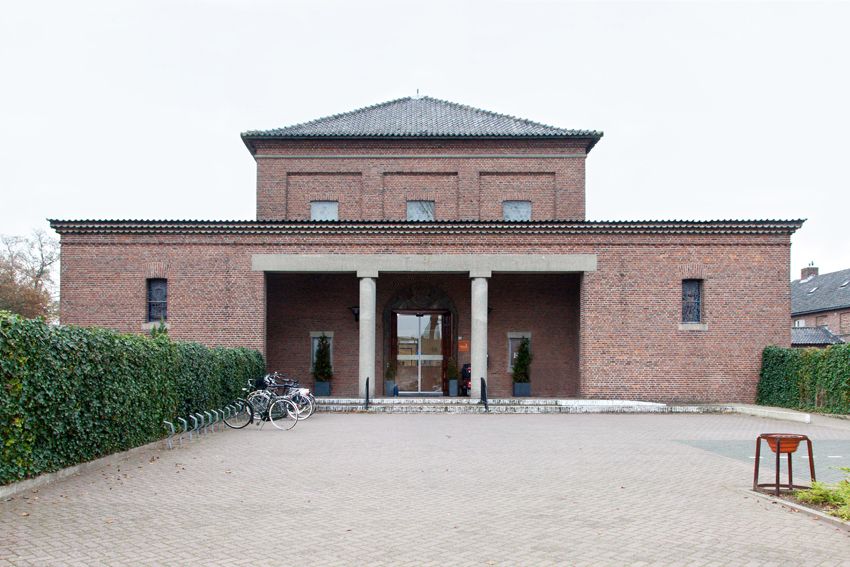 Voorzijde van het gebouw met baksteen gevel, zuilengang en fietsen