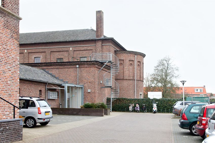 Parkeerplaats met de achterzijde van het gebouw en een buitentrap